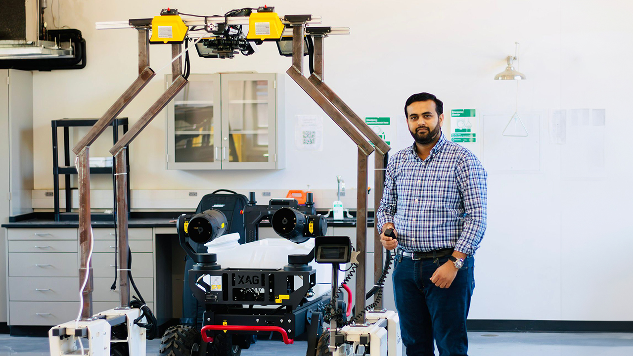 An Auburn assistant professor stands next to rover robot