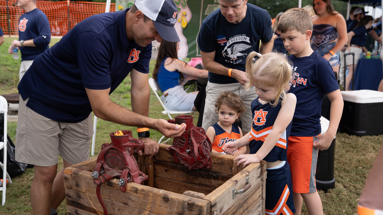 A man shows off a corn grinder to a few young children
