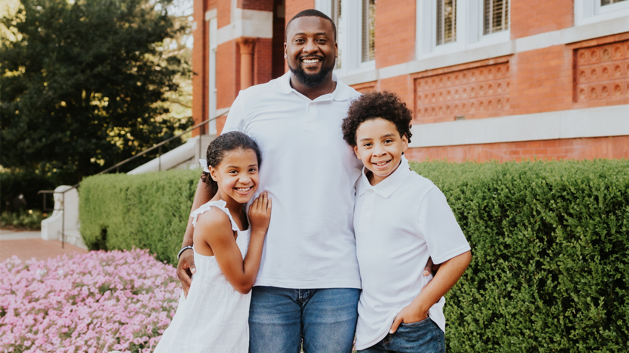 Churmell Mitchell poses with kids in front of Samford Hall