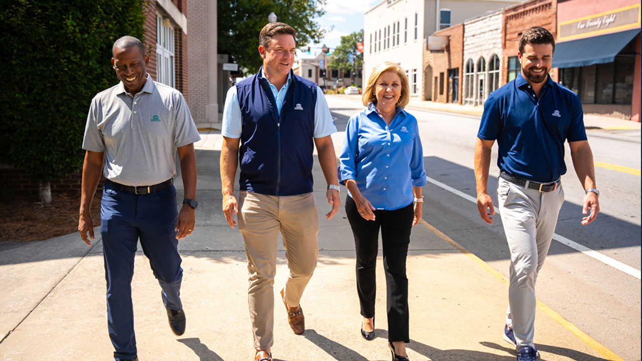 Jay Bland, far right, walks down a sidewalk with three other people