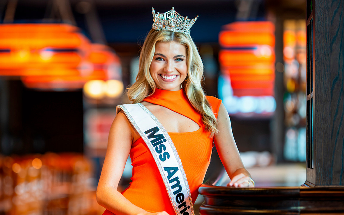 Miss America with crown and sash on staring into the camera.