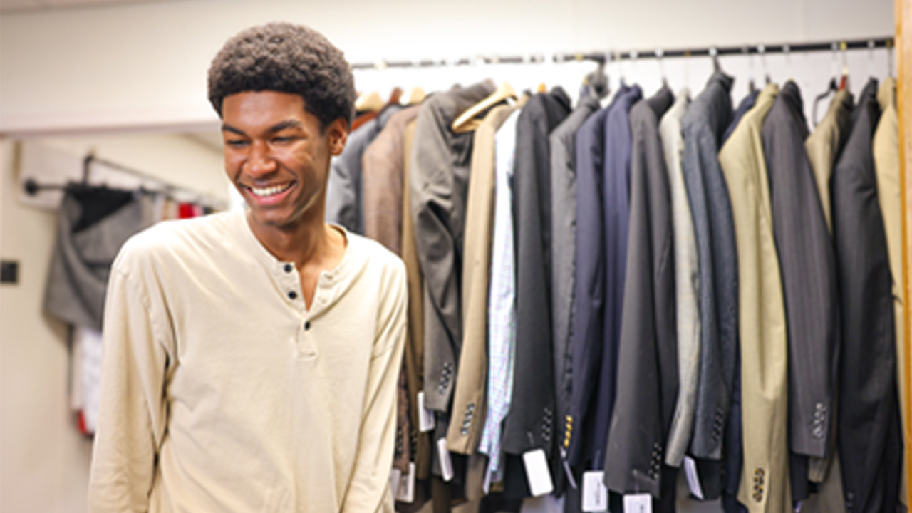 A student smiles at his options of new clothes