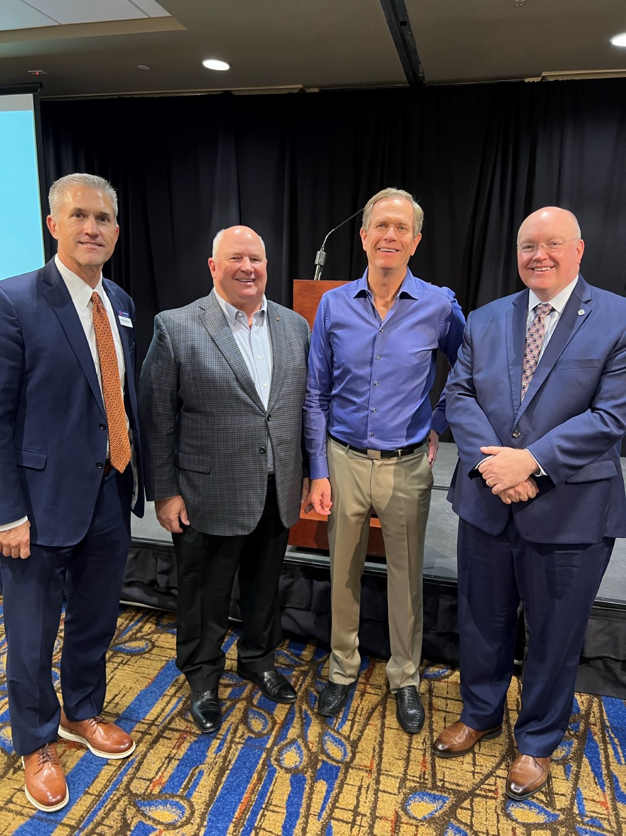 Four men standing before a podium smiling