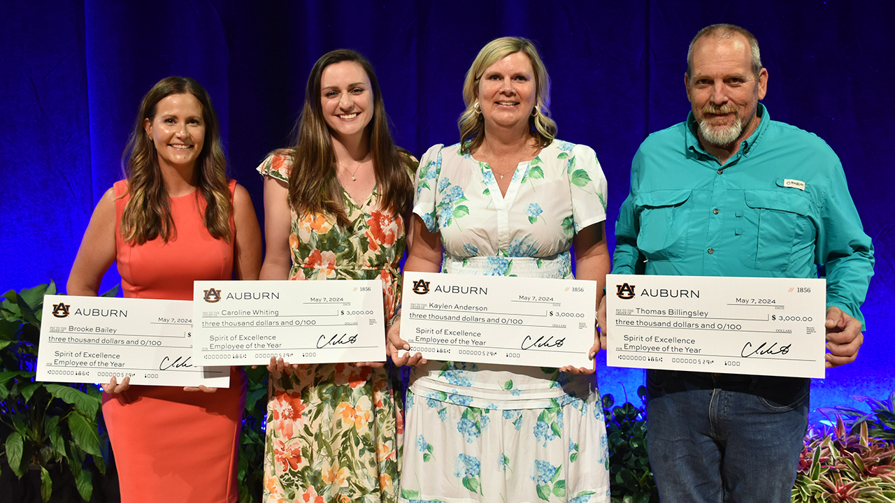 Four people holding cardboard checks