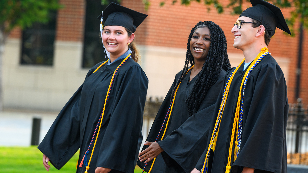 three graduates outside walking