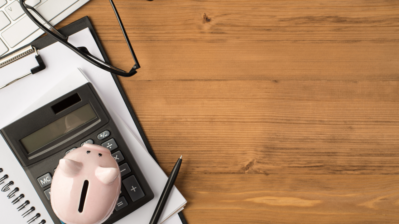 Piggy bank, calculator, notebook, and other items on desk