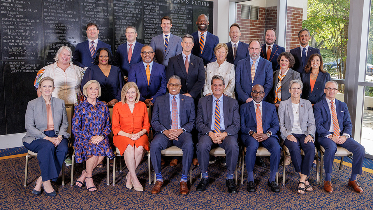 Members of the 2025 Auburn Alumni Association Board Members gather for a picture with some sitting in chairs and others standing in two rows behind them.