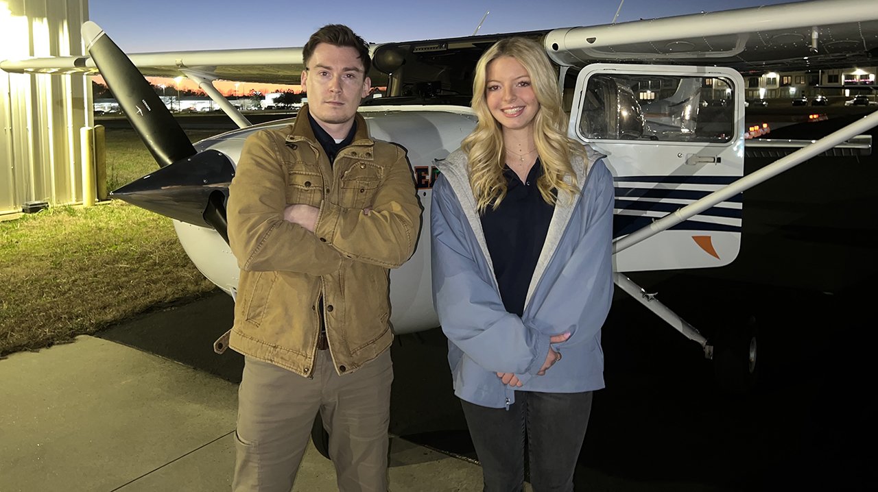 Management junior Ethan Franz standing beside plane with one of his flight students.