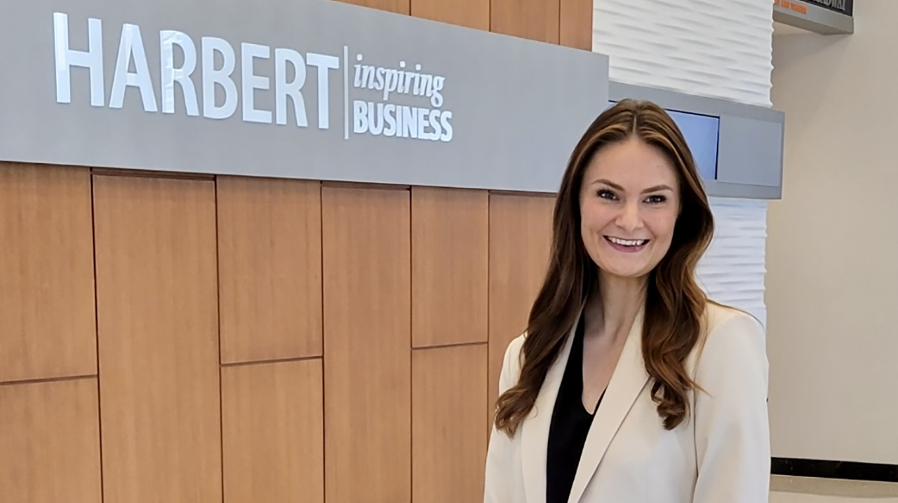 Student standing in front of Harbert College sign