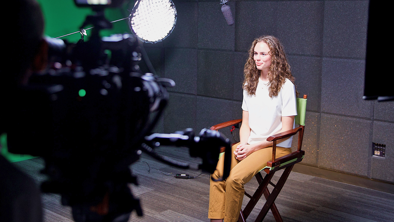 Female student sitting on tv set for interview