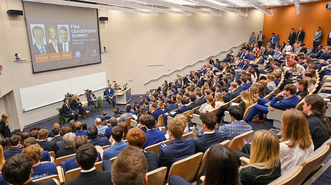 Panel of speakers in front of large audience