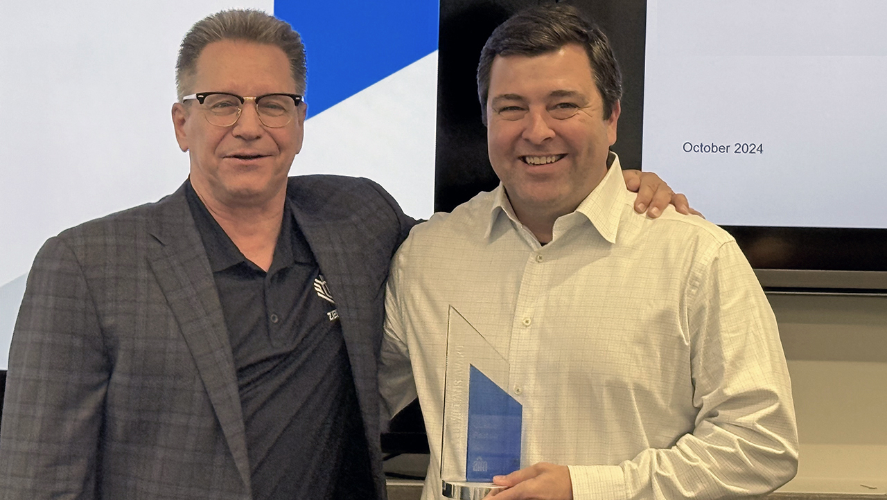 Two men standing with one holding award