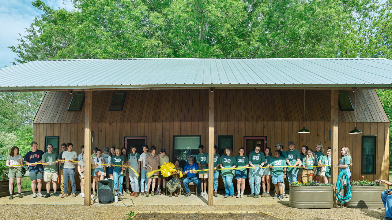 Students and clients cut the yellow ribbon at a newly built home