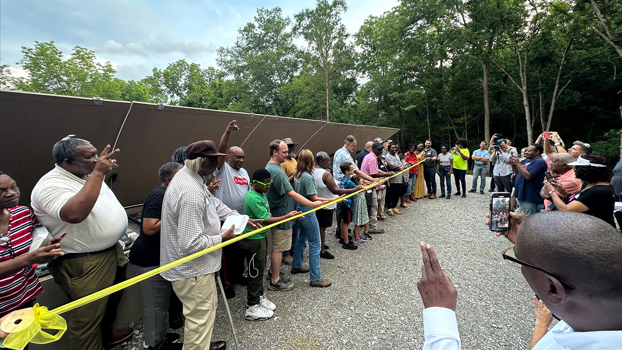 Community members and partners cut the yellow ribbon in front of the new treatment unit