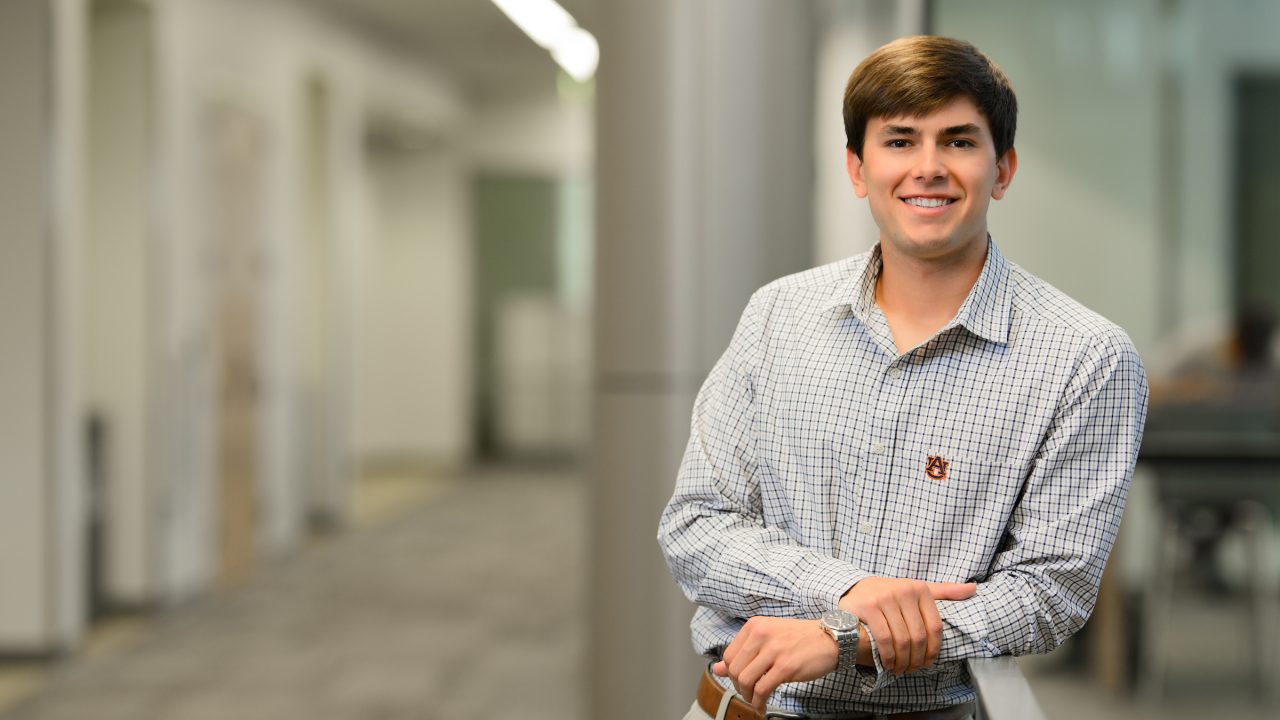 A young man crosses his arms and smiles for the camera