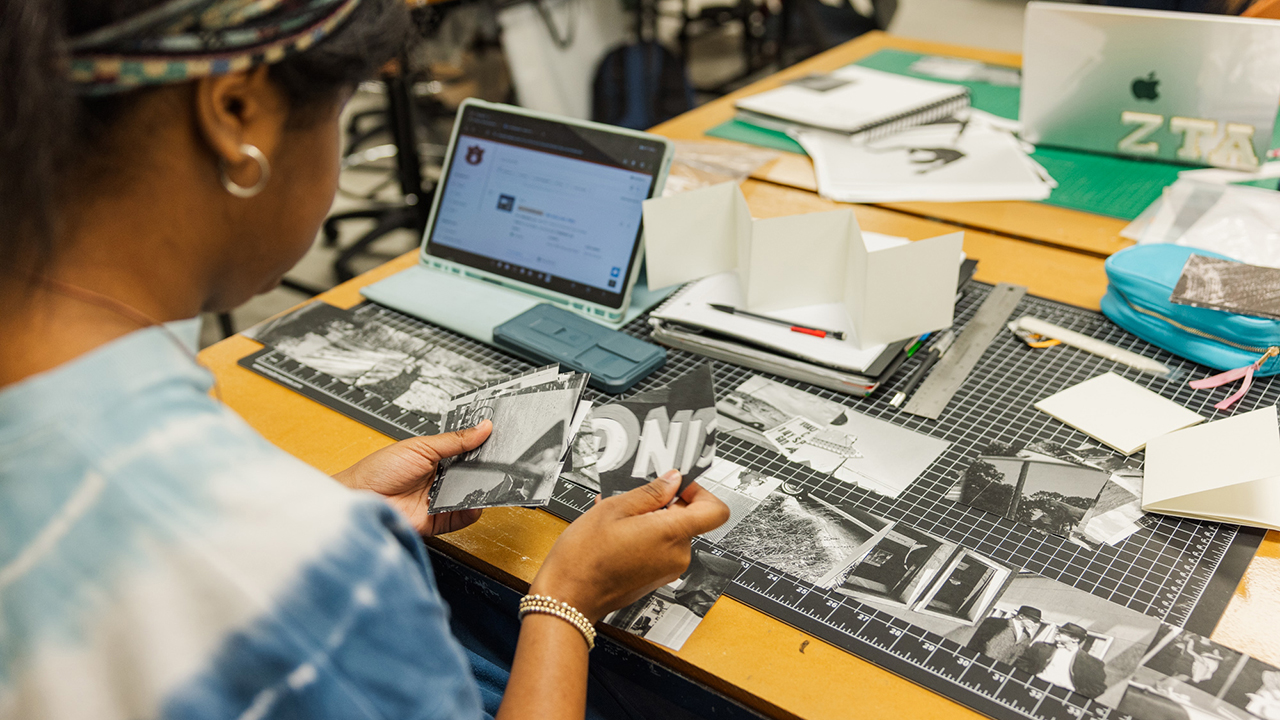 Student examining individual compositions in a graphic design studio