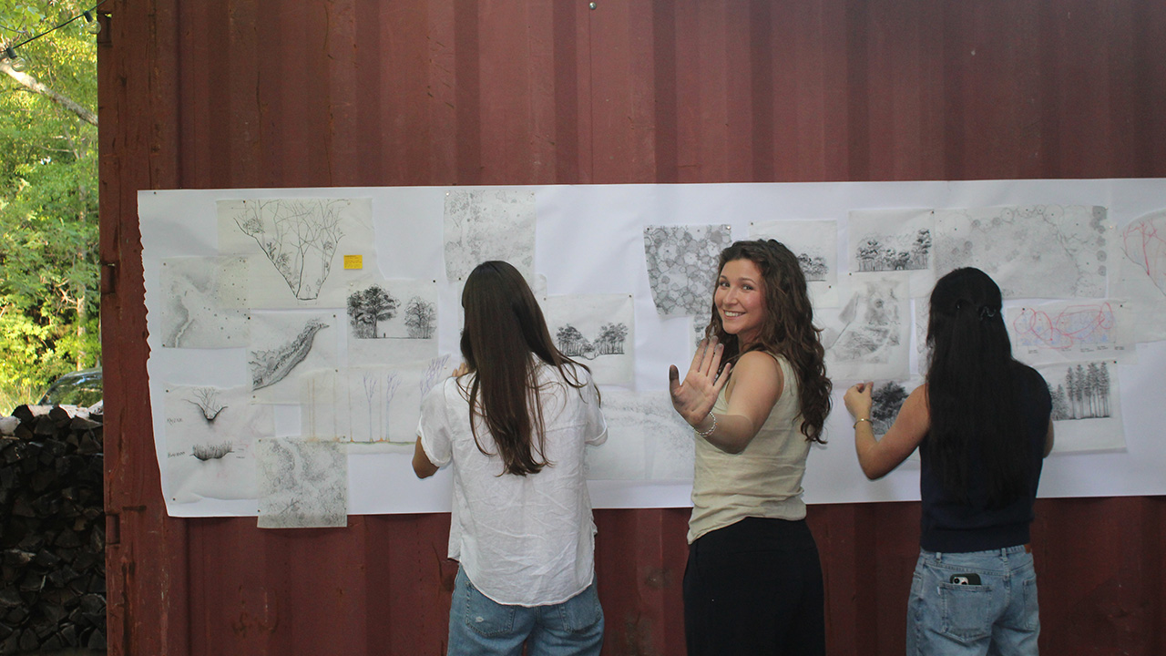 Bella Zanfardino posing in front of sketches with other students
