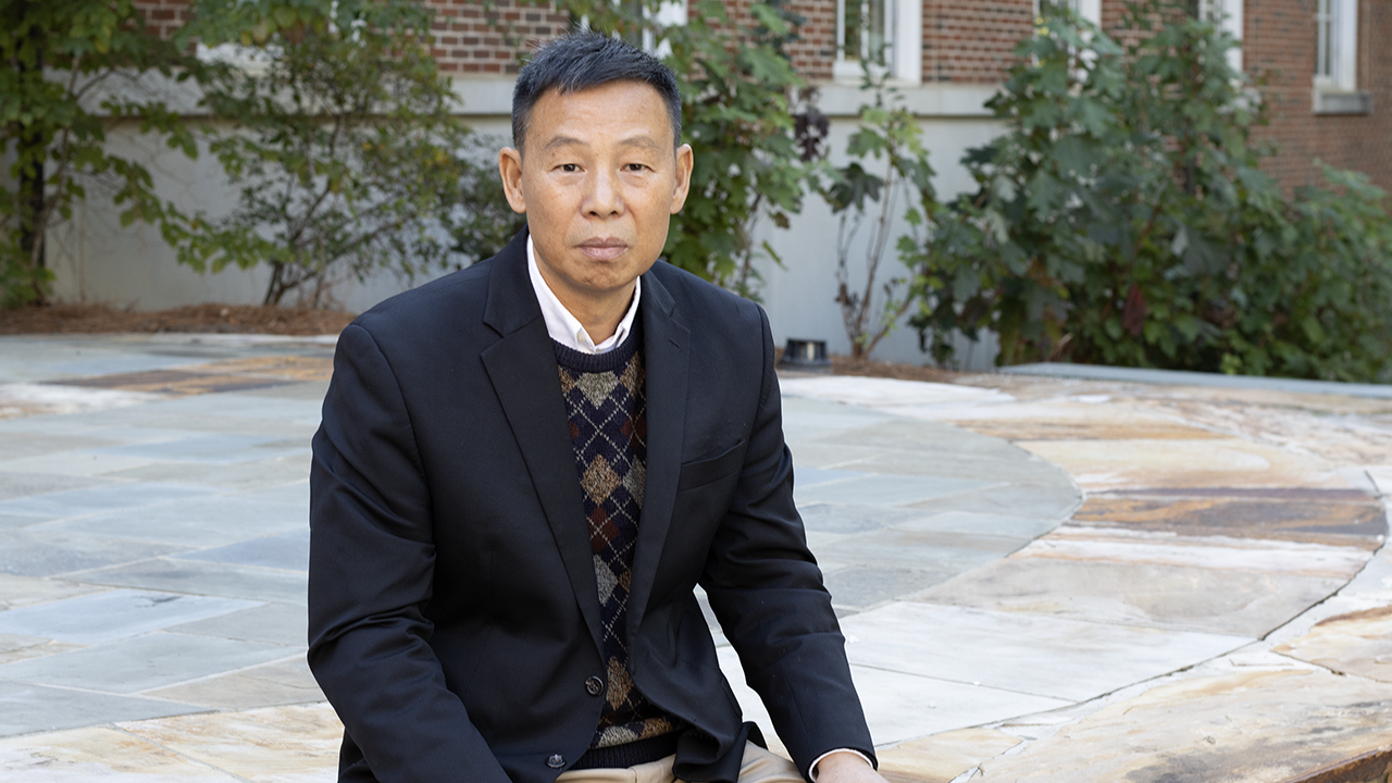 Daowei Zhang sits on patio at Auburn