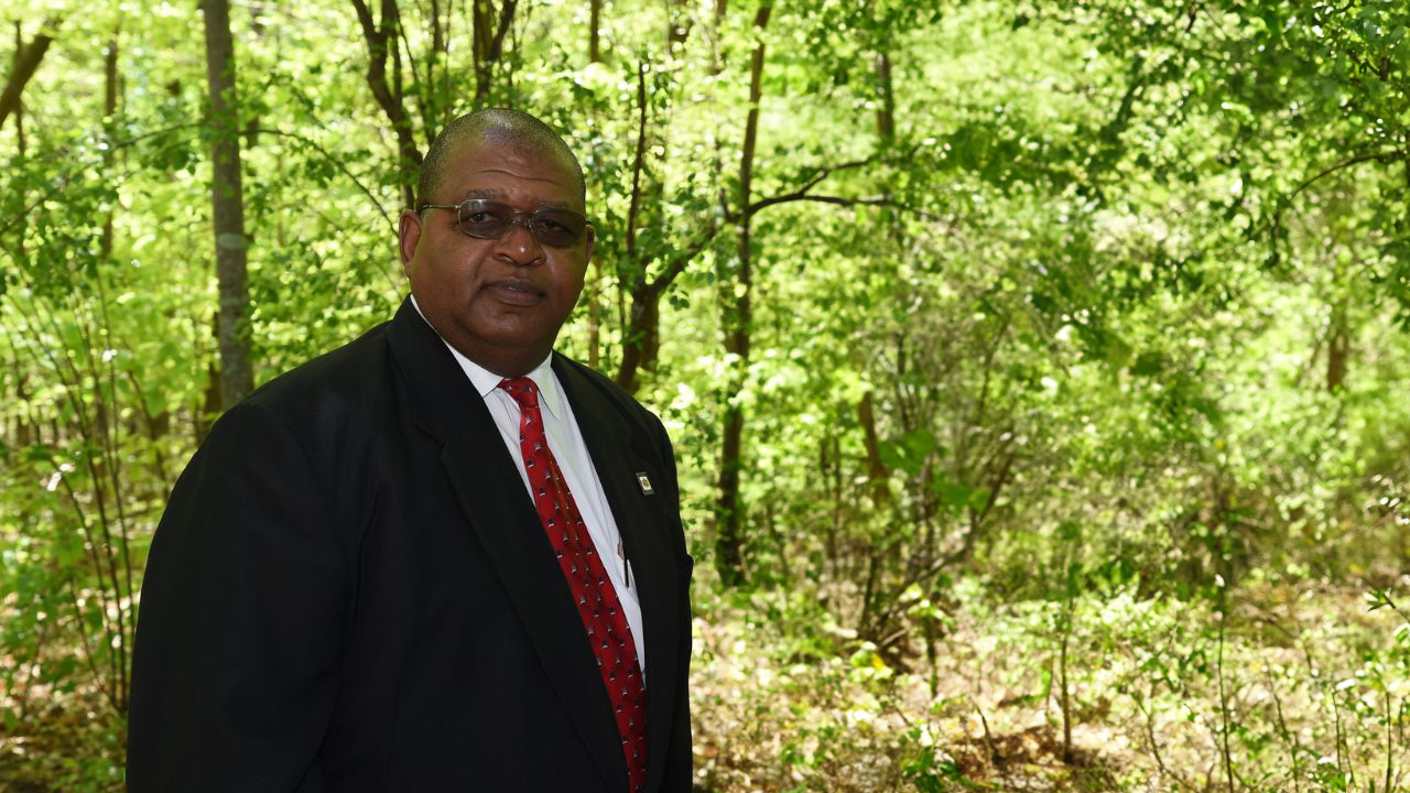 A man poses for a photo in the woods