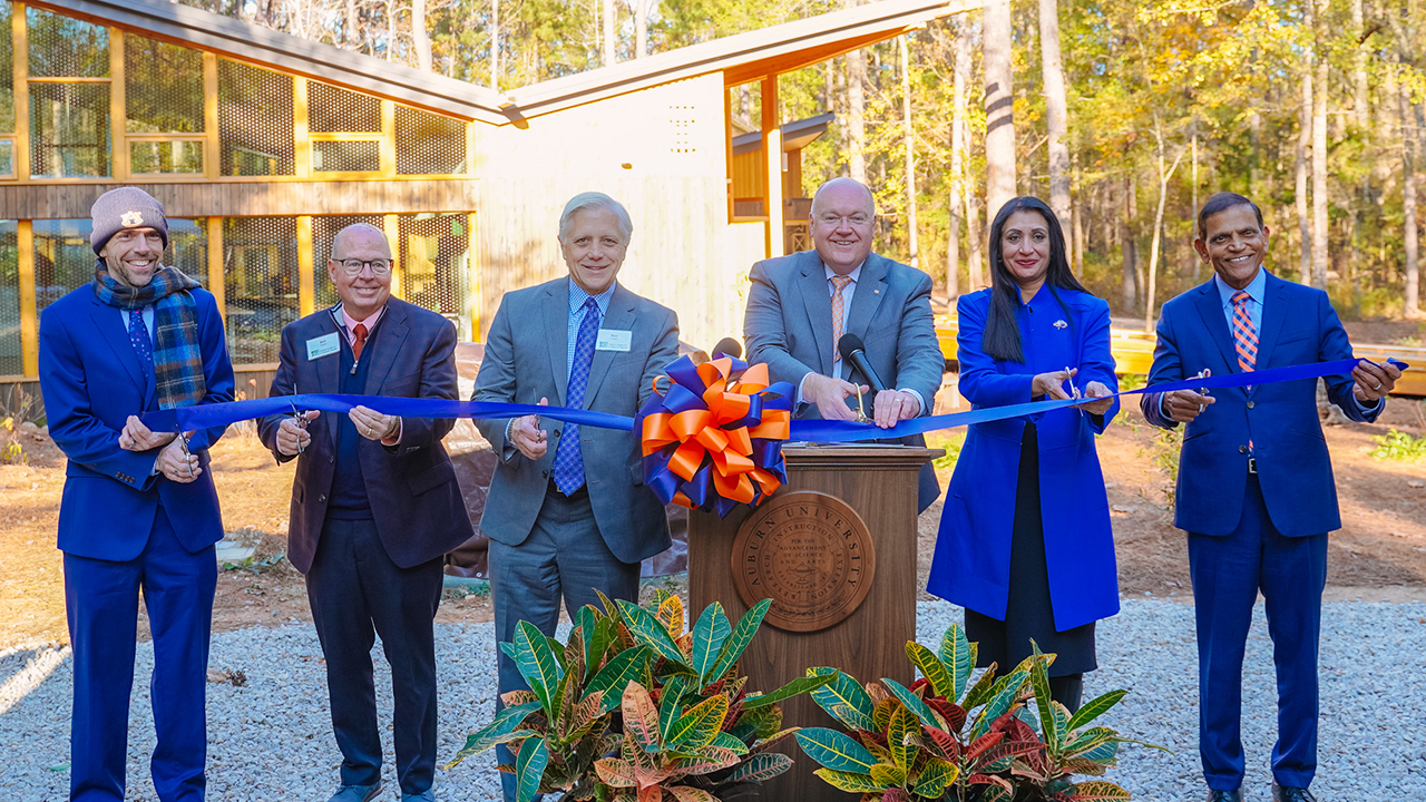 Auburn leadership pose at podium for the ribbon cutting.