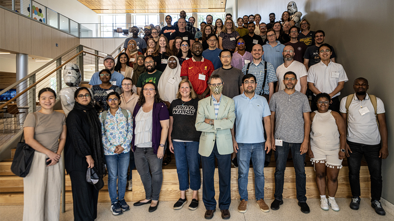 Large group of faculty, staff, and graduate students standing on a staircase inside a campus building during the AUSSI workshop.