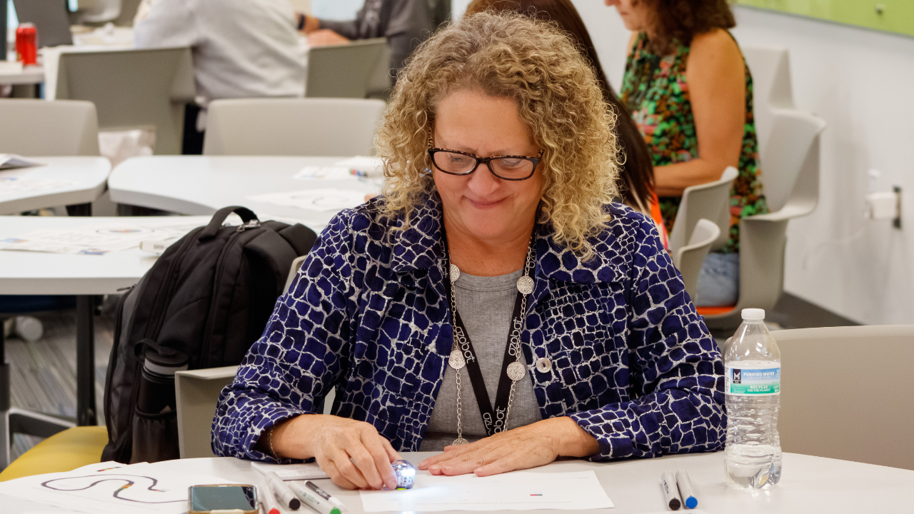 A participant smiles while programming a small robot during a hands-on workshop at the 2025 SERC conference.
