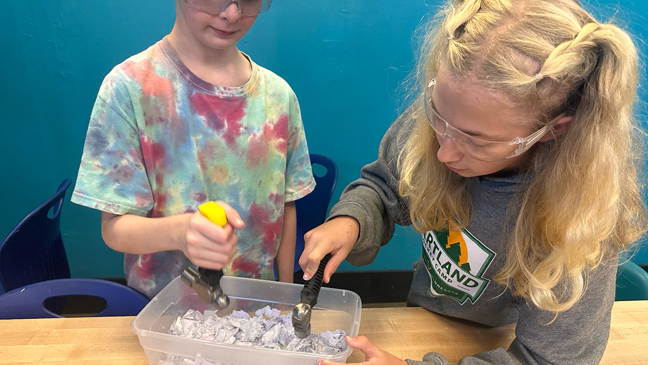 Students pound fibers in a plastic container.