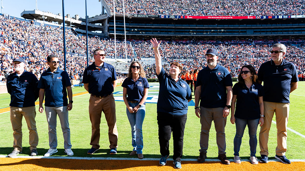 A group of academics are pictured on the football field of Jordan-Hare Stadium