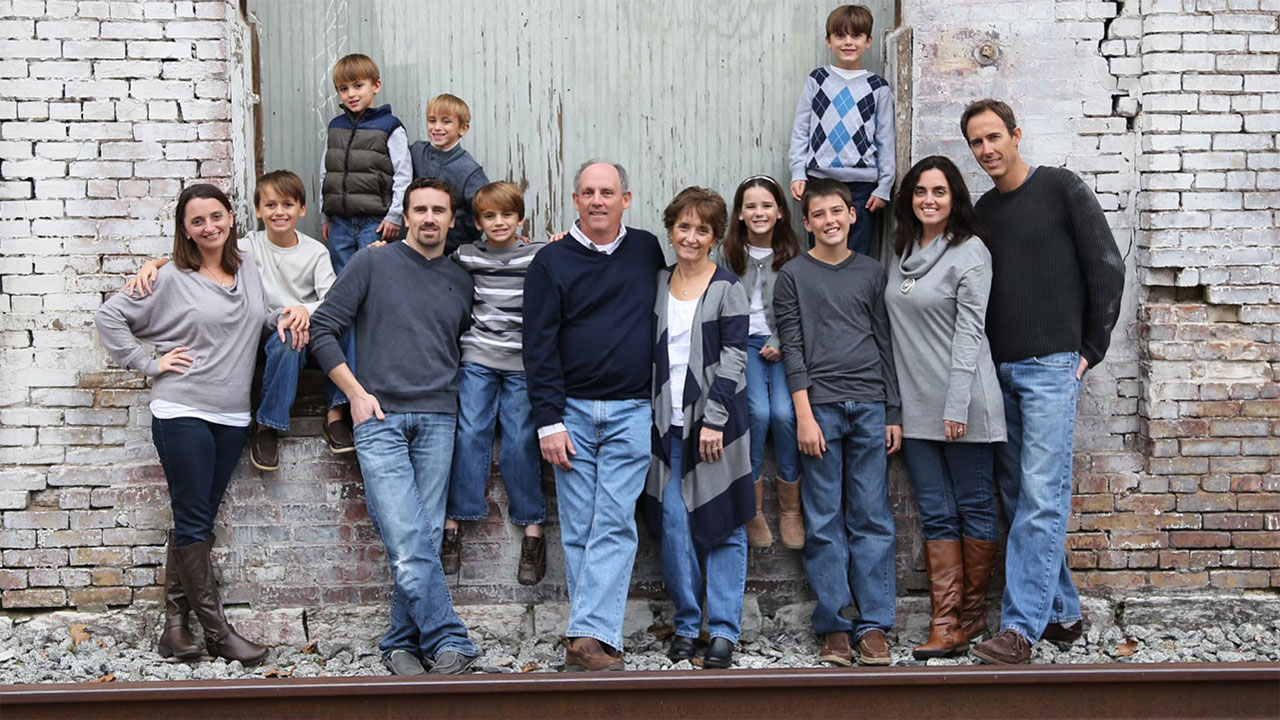 A group family photo outdoors in front of a brick wall.