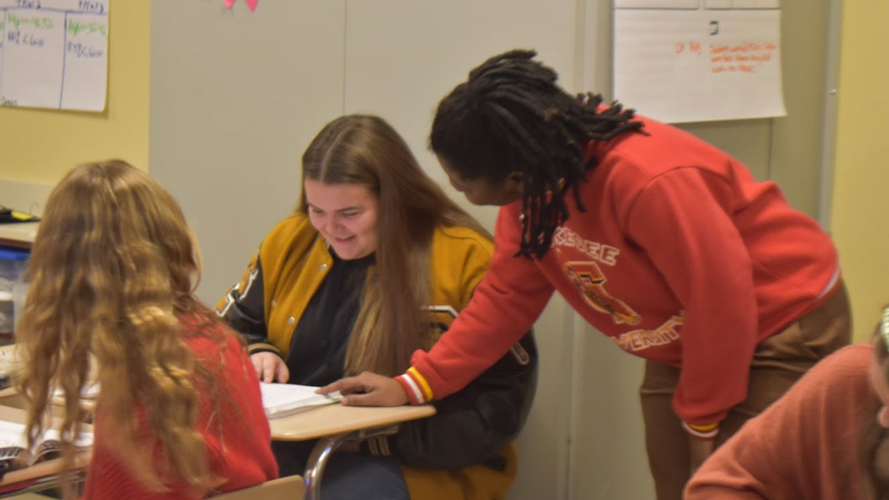 A student teacher works with a student inside a classroom.