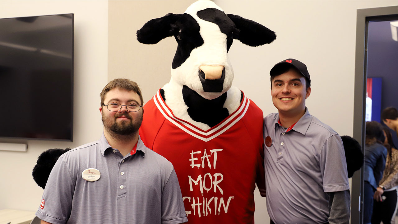 Two EAGLES students pose for a photo with the Chick-fil-A cow mascot