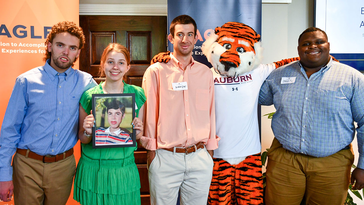 Several students stand side by side holding a framed photo of Scott Lawrence