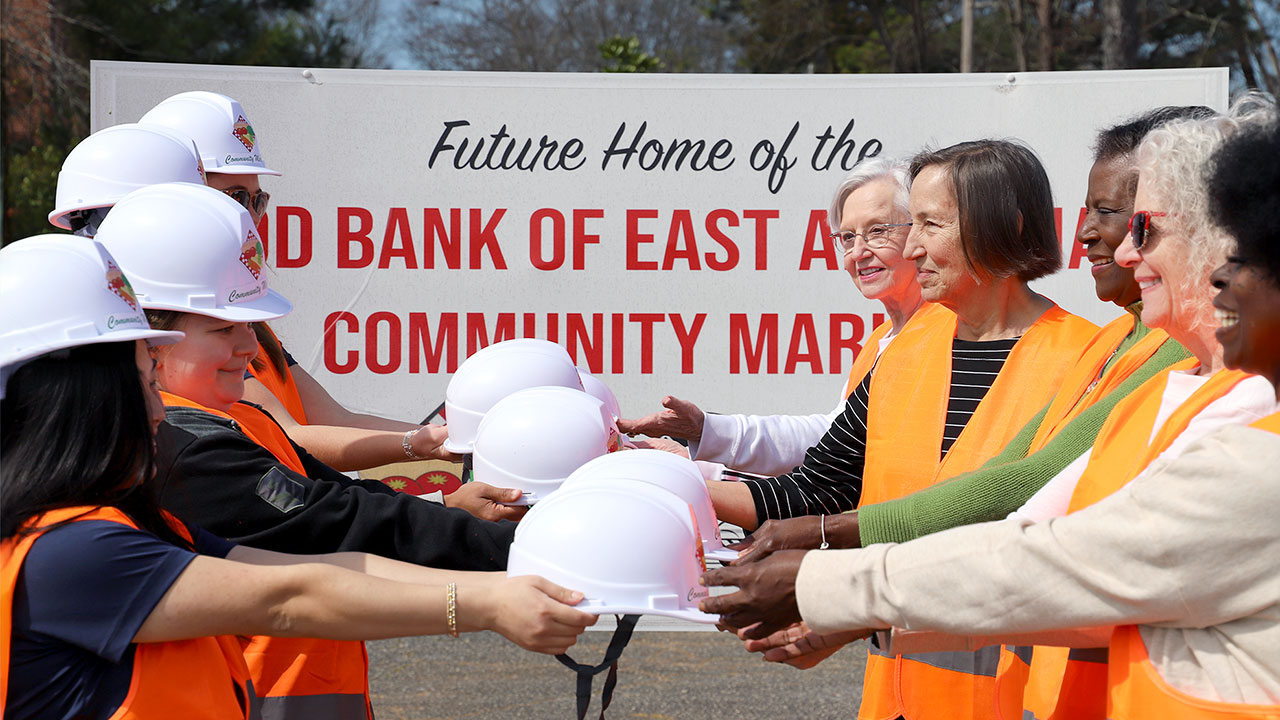 Representatives of Auburn's College of Education hand over construction hard hats to members of a community organization.