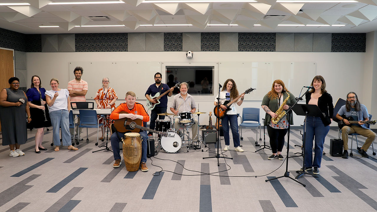 A member of the College of Education band plays a guitar.