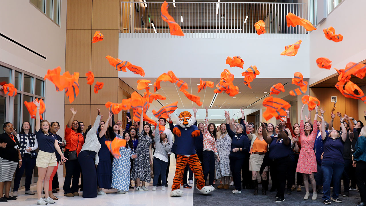 Faculty and staff throw construction vests into the air inside the new College of Education building. 