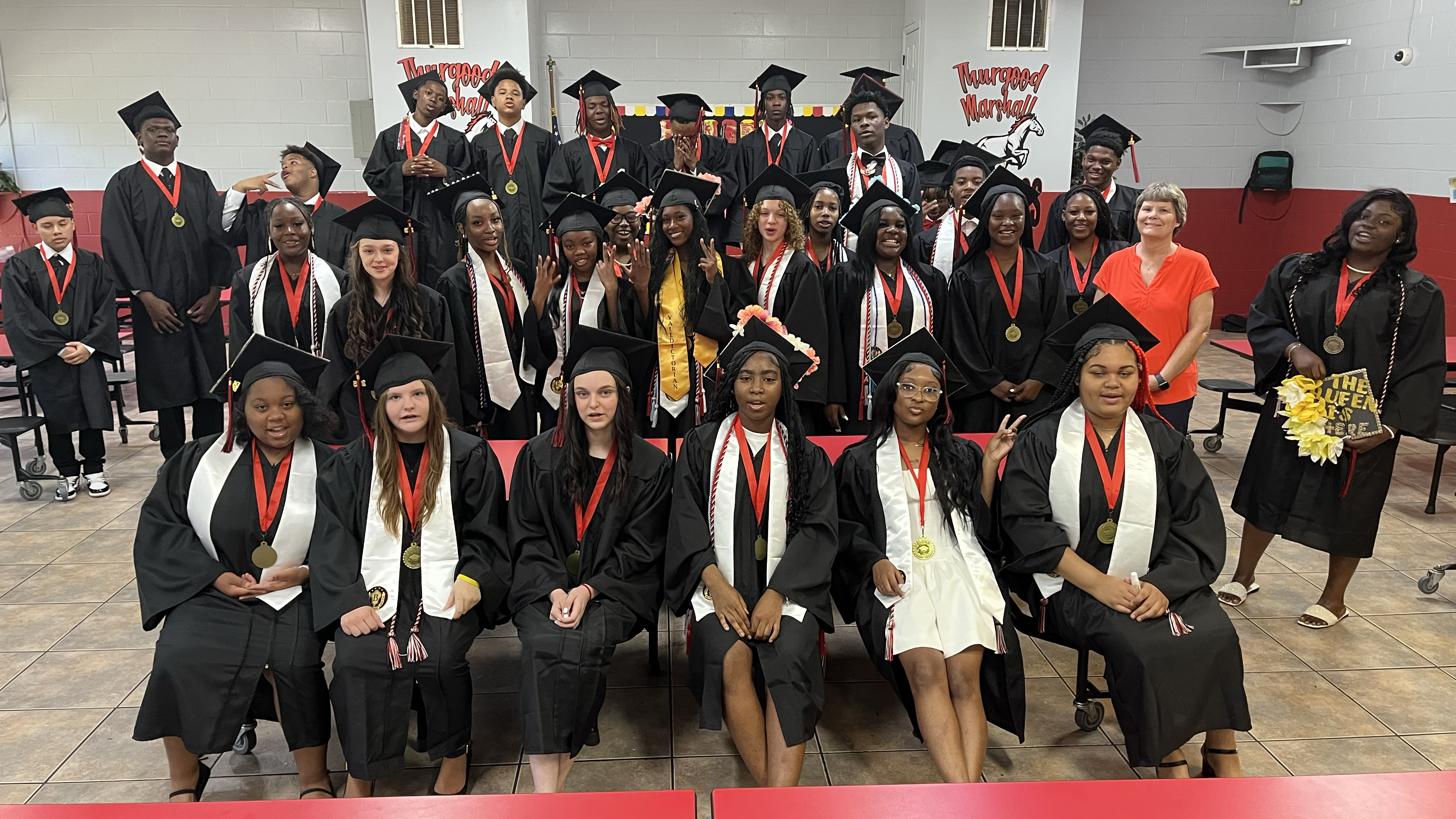 Eighth grade students from Thurgood Marshall Middle School pose in graduation caps and gowns.