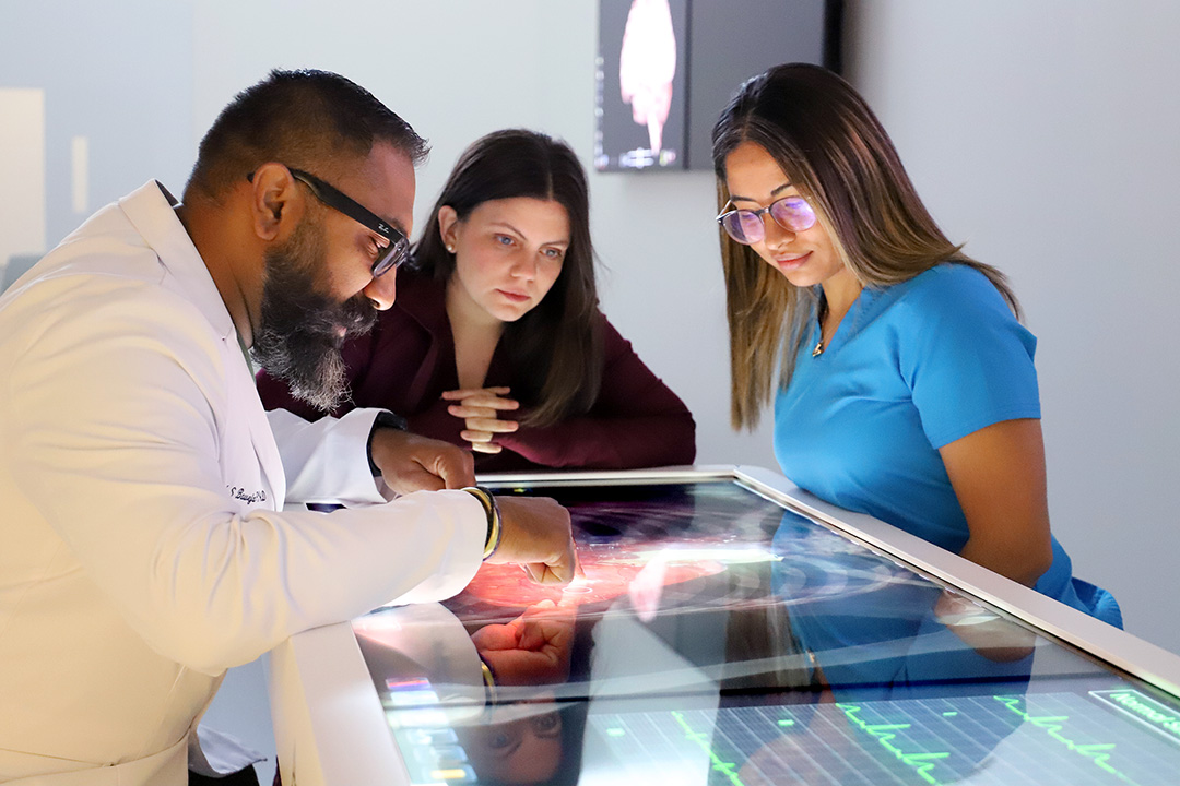Dr. Baweja and two students work on a digital anatomy table