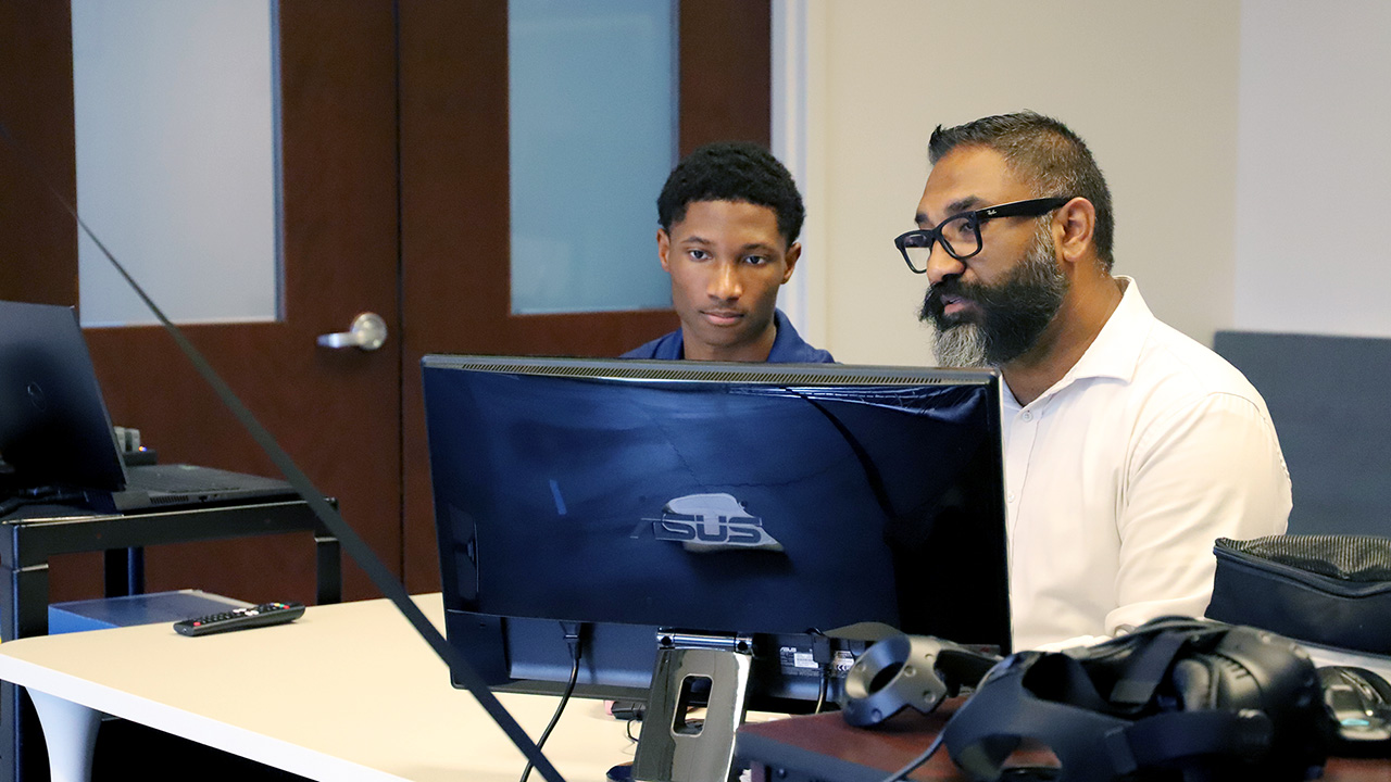 Jared Russell II and Dr. Harsimran Baweja look at a computer screen as they conduct research in the Sensorimotor and Rehabilitation Technology Lab.
