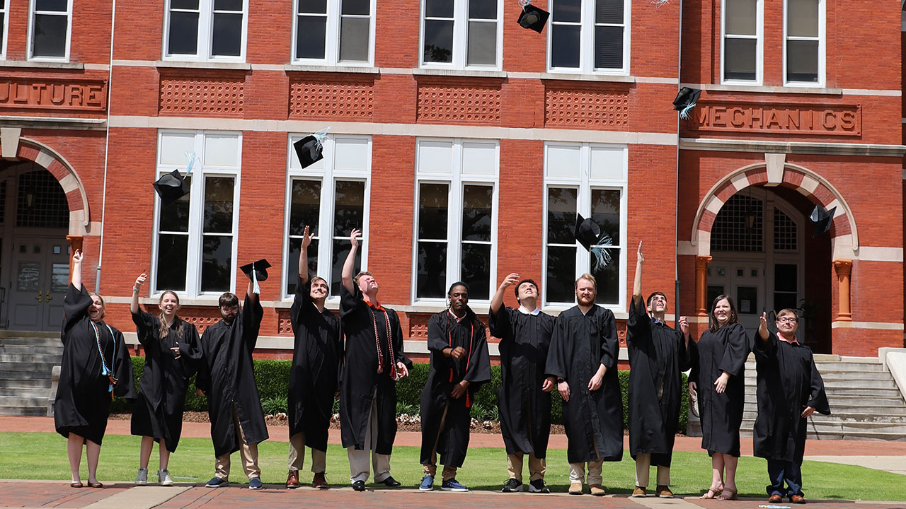 Members of a recent graduating class of the EAGLES Program toss their caps in celebration in front of Auburn