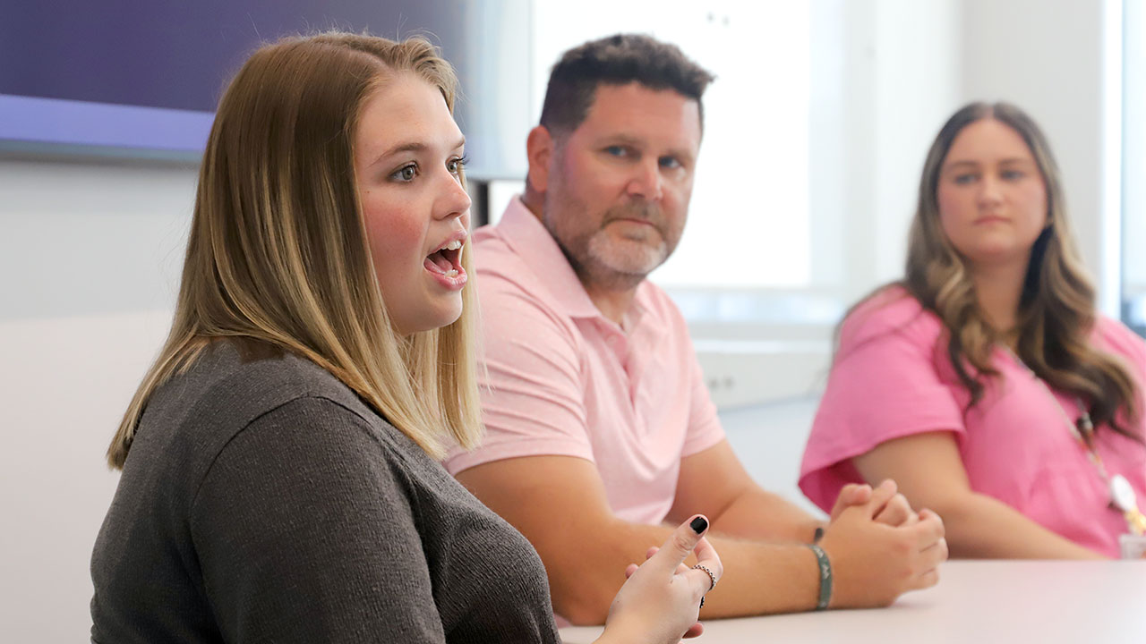 Three Auburn School Counseling alumni are pictured sitting and speaking to students inside a classroom.
