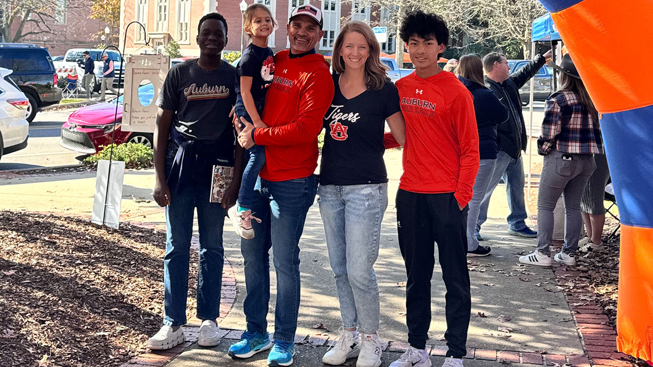 The Osburne family is pictured outdoors wearing Auburn garb while on Auburn