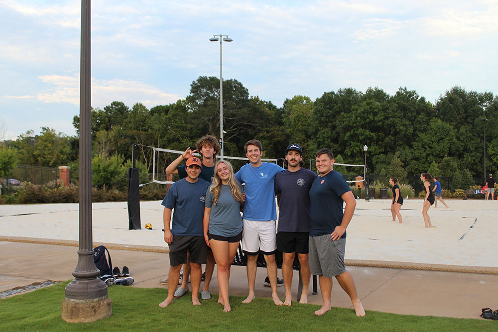 students in a group playing beach volleyball