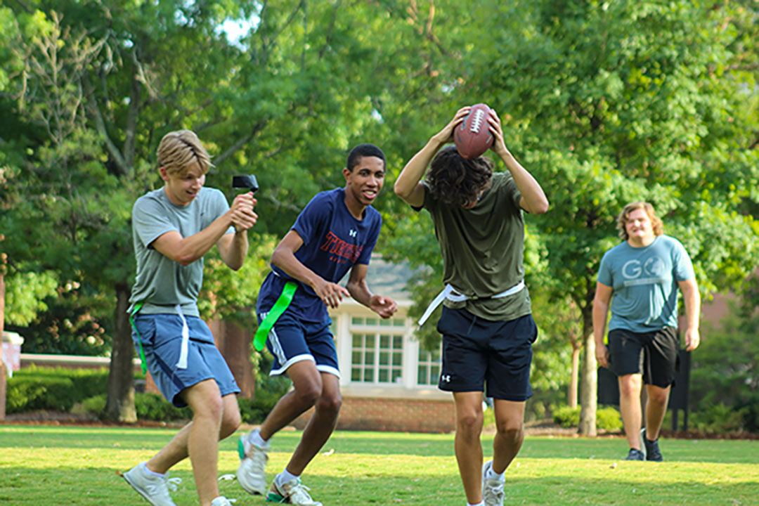 students playing flag football on samford lawn. Green grass and smiling faces abound