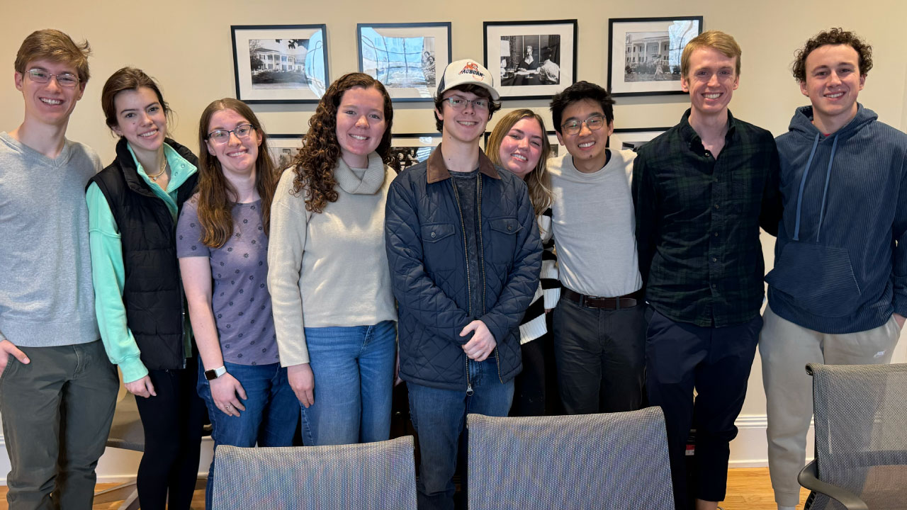 a group of students standing in cater hall with alumni allen li in near center. the students are all linking arms