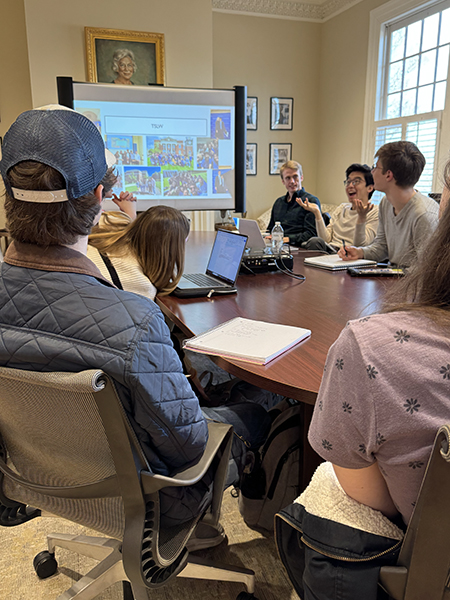 a group of students sit around a conference table in Cater Hall. a student sits in the foreground of the image as Li explains his truman scholarship