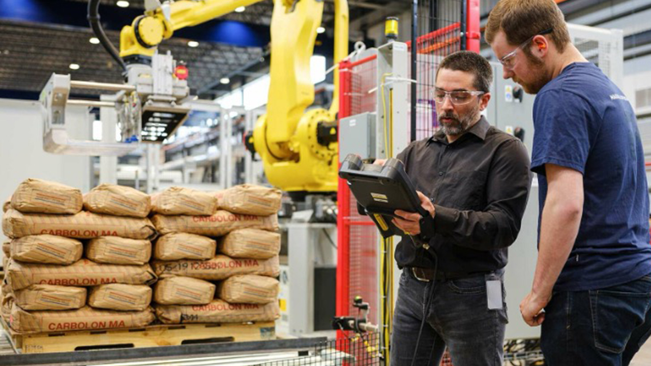 two men standing next to a pallet robot