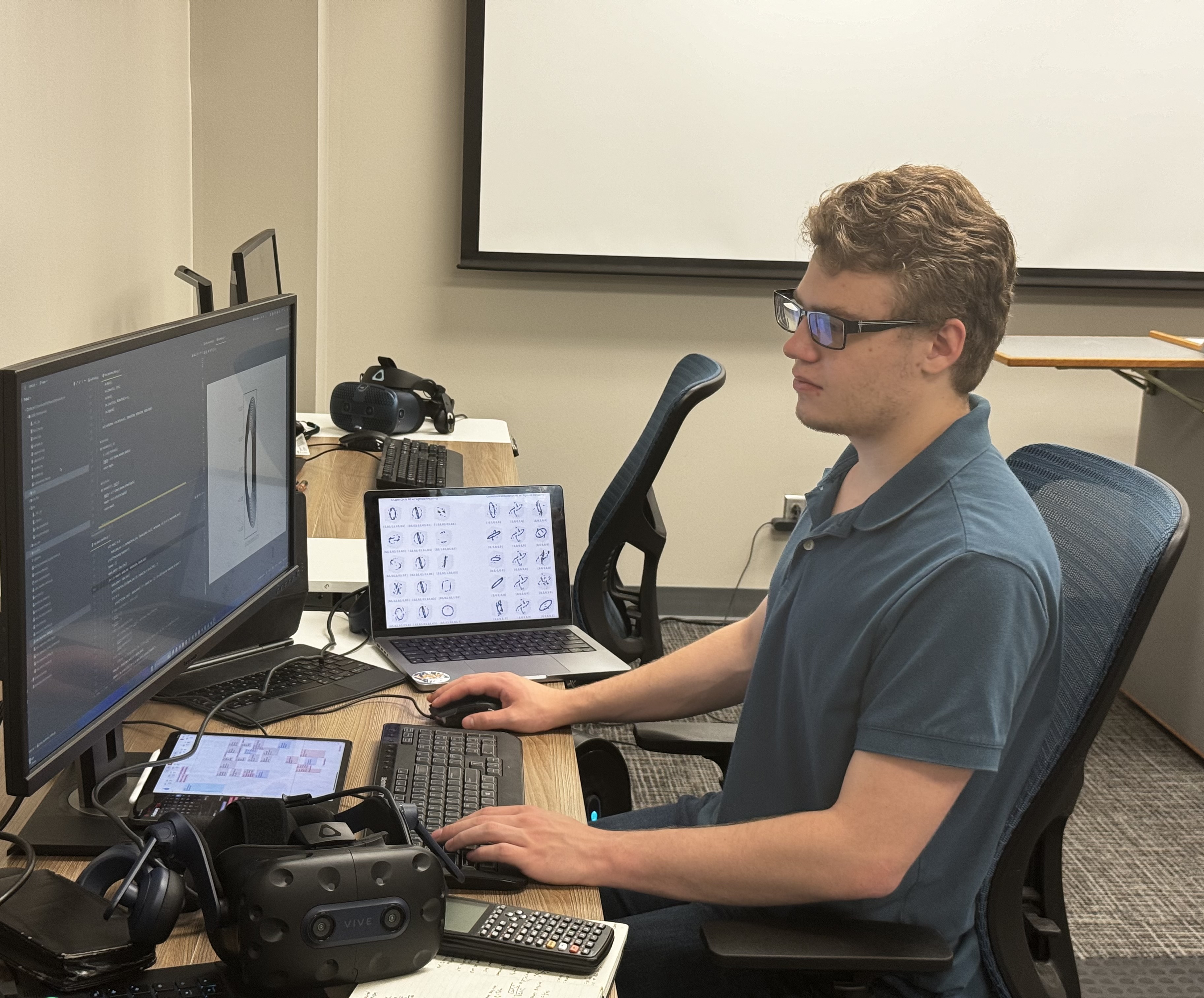 eirik is in a blue shirt and sitting in front of his computer doing research work