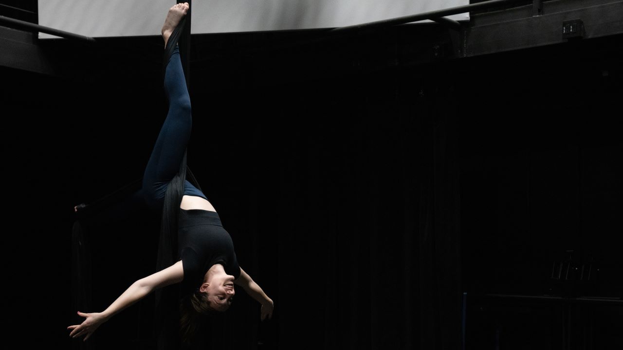 Sydney Pereira hanging upside down on aerial fabrics