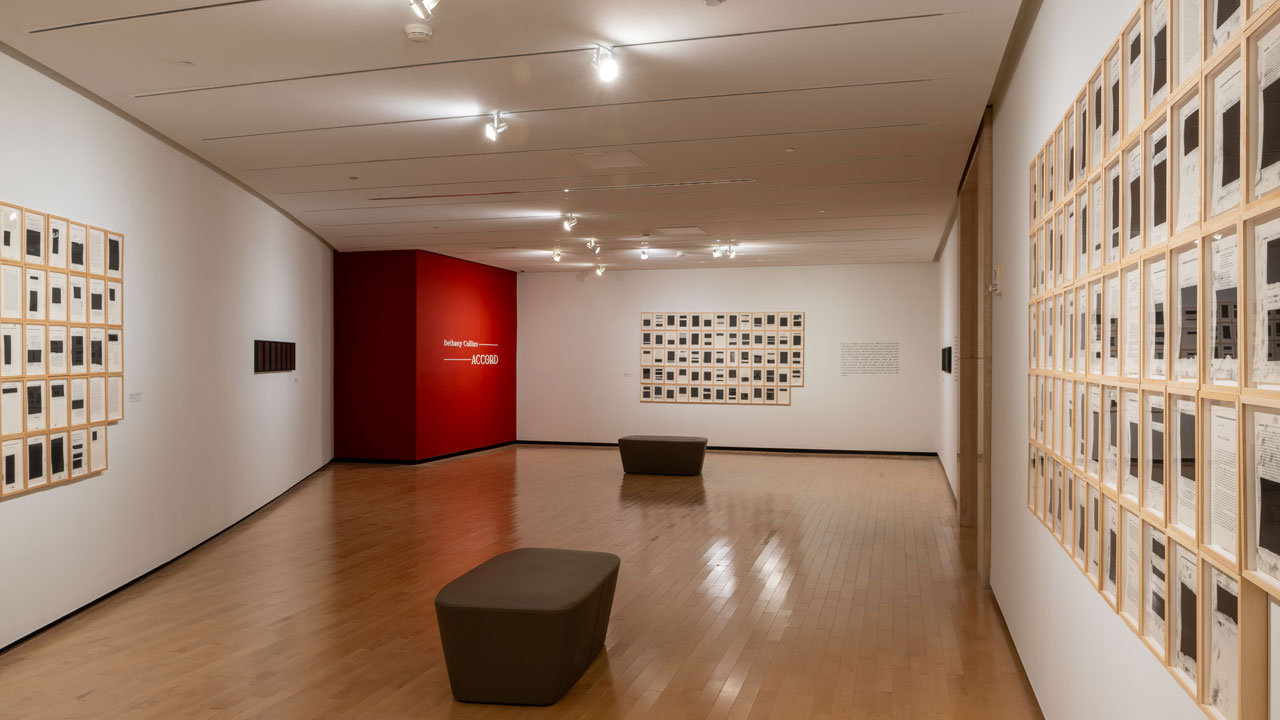 An empty museum gallery with large charcoal drawings and works on paper installed