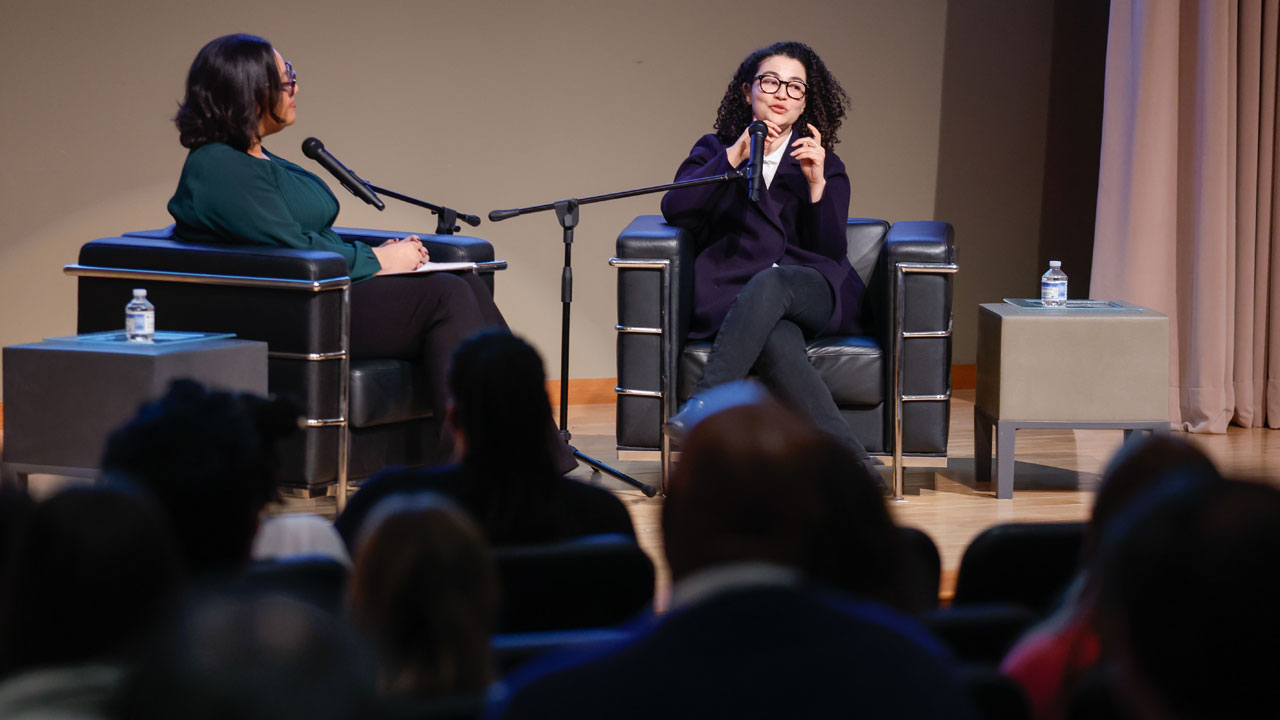 Two people sitting on stage in front of an audience